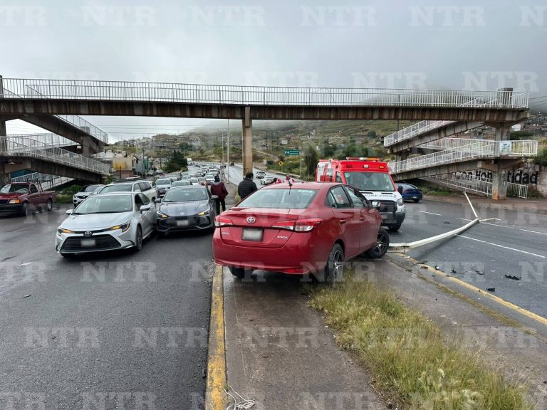 Brinca el camellón, derriba luminaria y provoca choque entre dos autos